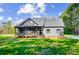Charming home with a covered porch and manicured lawn set against a backdrop of mature trees and a blue sky at 437 Cedar Grove Rd, Clover, SC 29710