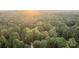 An aerial perspective captures a home encircled by lush forest and bathed in the soft glow of a sunrise or sunset at 463 Lake Wylie Rd, Belmont, NC 28012