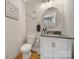 Stylish half bath with decorative mirror, modern vanity, neutral paint, and hardwood flooring at 463 Lake Wylie Rd, Belmont, NC 28012
