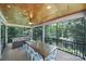Screened-in porch with rustic wood ceiling, fan, dining table, and comfortable seating at 463 Lake Wylie Rd, Belmont, NC 28012