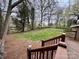 A spacious, grassy backyard view from a wooden deck with stairs and bordering fence with lots of trees at 4805 Horizon Cir, Charlotte, NC 28215