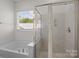 Bathroom featuring a garden tub, walk-in shower with glass door, and a bright window at 5813 Mcclintock Dr, Denver, NC 28037