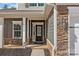 Inviting front porch features stacked stone accents, comfortable seating, and a stylish front door at 5813 Mcclintock Dr, Denver, NC 28037
