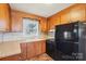 Close-up of kitchen featuring wood cabinets, a window, black stove and refrigerator at 839 Oak Grove Rd, Kings Mountain, NC 28086