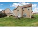 Back of home with a wooden deck overlooking the large yard and blue skies at 9391 Leyton Dr, Harrisburg, NC 28075