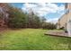 Well-maintained backyard with green grass, trees, and a small wooden deck at 9391 Leyton Dr, Harrisburg, NC 28075