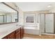 Bright bathroom with a double sink vanity, a soaking tub, and a walk-in shower at 9391 Leyton Dr, Harrisburg, NC 28075