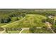 Expansive aerial view of a lush, green property with scattered trees and a long driveway leading to a quaint house at Lot 14 Mayes Meadow Dr, Cornelius, NC 28078