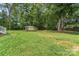 A large, grassy backyard featuring mature trees and a storage shed at the far end at 145 Mcbride Dr, Rockwell, NC 28138
