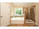 Bathroom featuring a soaking tub, glass-enclosed shower, and a bright window at 1800 Robbins Meadows Dr, Waxhaw, NC 28173
