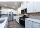 Well-lit kitchen featuring stainless steel appliances, white cabinets, quartz countertops, and gray wood flooring at 3100 Cheyney Park Dr, Charlotte, NC 28269