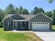 Charming one-story home featuring neutral siding, a well-manicured lawn, and an attached two-car garage at 325 East St, Heath Springs, SC 29058