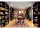 Handsome home office featuring custom built-in shelving, a brick wall, and hardwood floors at 4313 Kingswood Rd, Charlotte, NC 28226