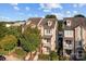 Aerial view of a brick townhome with balconies nestled among lush trees under a blue sky at 735 Amalfi Dr, Davidson, NC 28036