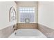 Bathroom featuring a tub with tiled surround and a glass block window at 12124 Red Rust Ln, Charlotte, NC 28277