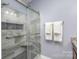 This shower features gray marble styled tiled walls, a built-in niche, and glass doors at 1512 Brooksland Pl, Waxhaw, NC 28173
