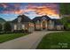 Stunning two-story home with a three-car garage and a professionally landscaped front yard under a dramatic sunset sky at 19216 Peninsula Shores Dr, Cornelius, NC 28031