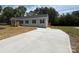 Long concrete driveway leads to a charming gray home with black shutters, set against a backdrop of mature trees at 2070 Travis Rd, Conover, NC 28613