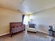 Neutral-toned bedroom showcasing a crib, chair, and plenty of natural light through a large window at 3426 Dominion Green Dr, Charlotte, NC 28269