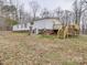 Back exterior view of the home featuring a wooden deck, grassy yard, and mature trees at 40701 Nc 740 Hwy, New London, NC 28127