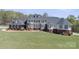 A vast home with a dark roof and brick facade, surrounded by a lush lawn, showcasing its grand appearance at 447 Willow Pond Ln, Hiddenite, NC 28636