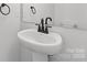 Cozy powder room with modern black hardware, white pedestal sink and neutral wall color offers a clean space at 615 W Stanly W St, Stanfield, NC 28163