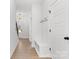 Hallway featuring light walls, wood floors, coat hooks, white doors, storage bench, and modern light fixtures at 615 W Stanly W St, Stanfield, NC 28163