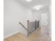 Upstairs hallway features wood-look flooring, white walls, and black metal balusters with wood handrail at 615 W Stanly W St, Stanfield, NC 28163