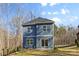 The backyard of this two-story home features blue siding, a well-manicured lawn, and mature trees at 615 W Stanly W St, Stanfield, NC 28163