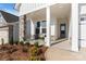Inviting front porch with stone pillars, comfortable seating, tasteful landscaping, and a beautifully stained front door at 1132 Meander Ln, Waxhaw, NC 28173