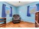 Bright bedroom featuring hardwood floors, two windows with blue curtains, and a comfortable armchair at 1802 Young Dr, Conover, NC 28613