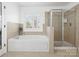 Well-lit bathroom features a modern tub, glass-enclosed shower, and tiled walls at 604 Wisteria Walk Way, Fort Mill, SC 29715