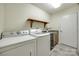 Bright laundry room with white washer and dryer, sink, countertop, wooden shelf, and neutral walls at 974 Platinum Dr, Fort Mill, SC 29708