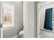 A well-lit bathroom leads into a carpeted bedroom with blue curtains and natural light from a nearby window at 3334 Cloninger Rd, Dallas, NC 28034