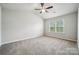 Spacious carpeted bedroom with a ceiling fan and natural light from the window at 10036 Brittondale Ln, Charlotte, NC 28215