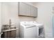 Functional laundry room with a stainless steel sink, modern washer, and dryer, and storage cabinets at 10421 Superb Ln, Charlotte, NC 28215