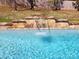 Close-up of stone waterfall feature cascading into the clear blue water of the in-ground swimming pool at 1301 Huckleberry Dr, Lincolnton, NC 28092