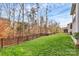 Backyard featuring a green lawn bordered by a metal fence and mature trees and shrubs at 1809 Mill Creek Sw Ln, Concord, NC 28025