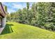Manicured backyard with lush green grass, surrounded by mature trees and an iron fence at 1809 Mill Creek Sw Ln, Concord, NC 28025