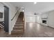 Open concept living room with a staircase, ceiling fan, and a cozy fireplace with white painted brick at 1921 Woodridge Dr, Hickory, NC 28602
