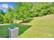 Lush backyard featuring a well-maintained lawn, mature trees, and cooling unit, creating a private outdoor oasis at 1923 Caprington Dr, Fort Mill, SC 29707