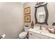 Neutral-toned half bathroom features decorative mirror, white vanity, and attractive wall decor at 25 Blenheim Ne Ct, Concord, NC 28025