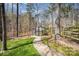 Backyard greenhouse nestled amongst trees, accessible by brick path and perfect for gardening enthusiasts at 25 Blenheim Ne Ct, Concord, NC 28025