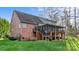 Back exterior of a brick home showcasing a screened porch, stairs, and a spacious green yard with trees at 2846 Snead Ne Ct, Conover, NC 28613