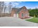 Brick home featuring a three-car garage and a long, curved driveway, surrounded by mature trees and landscaping at 2846 Snead Ne Ct, Conover, NC 28613
