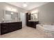 Bright bathroom with double vanity, large soaking tub with decorative tile, and a beautiful chandelier at 4225 Jasmin May Dr, Charlotte, NC 28226