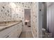 Bathroom featuring butterfly wallpaper, double vanity, and a view into the pink bedroom at 4225 Jasmin May Dr, Charlotte, NC 28226