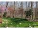 A spacious backyard featuring a lush lawn with trees and flowering shrubs bordering a black fence at 4232 Belle Meade Cir, Belmont, NC 28012