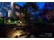 Backyard with stone steps, lush greenery, and night lighting, creating a magical outdoor ambiance at 4232 Belle Meade Cir, Belmont, NC 28012