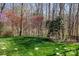 A spacious backyard featuring a lush lawn with trees and flowering shrubs bordering a black fence at 4232 Belle Meade Cir, Belmont, NC 28012